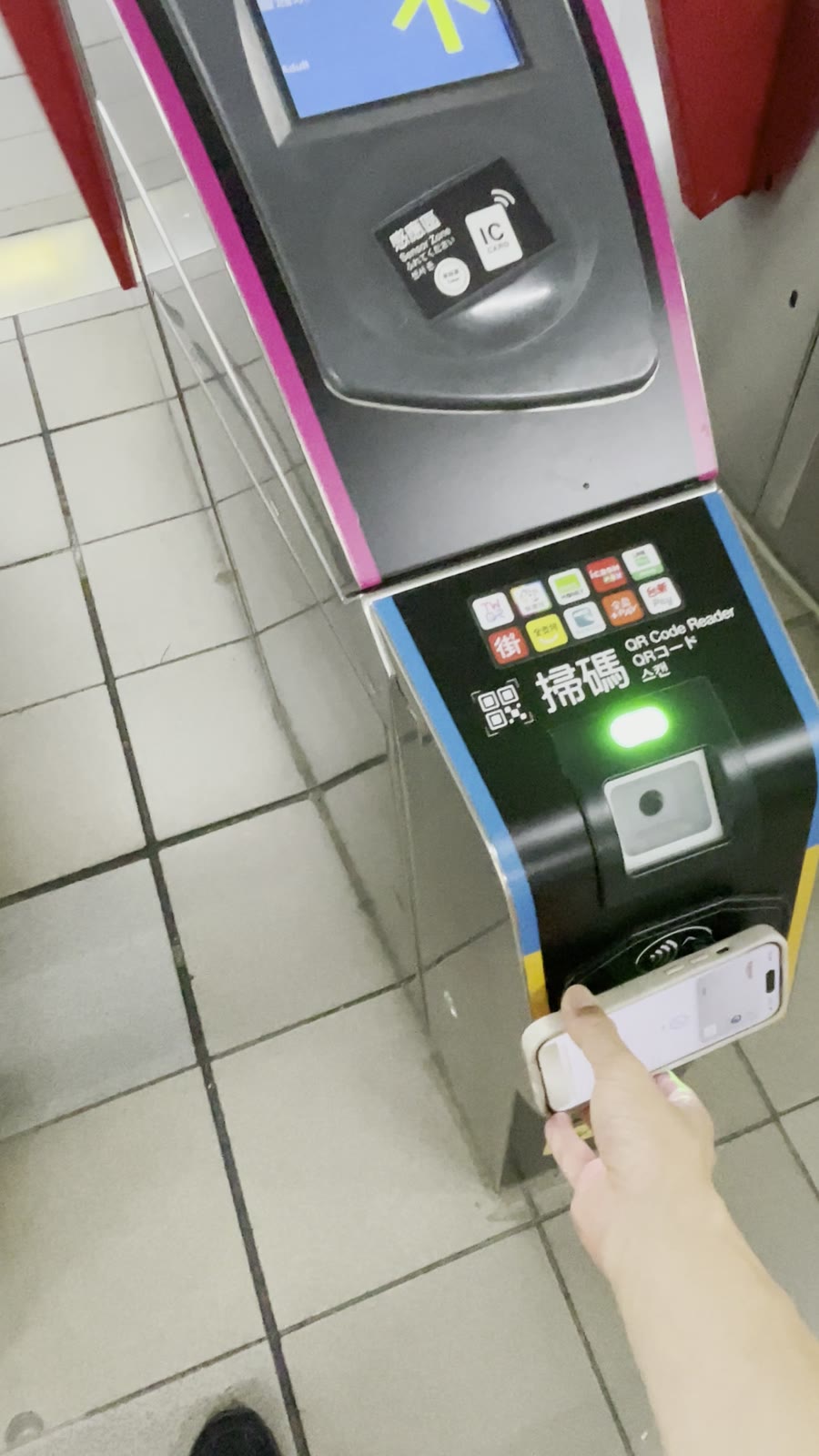 台北MRTの改札下部にあるクレジットカード用リーダーにiPhoneをかざす様子